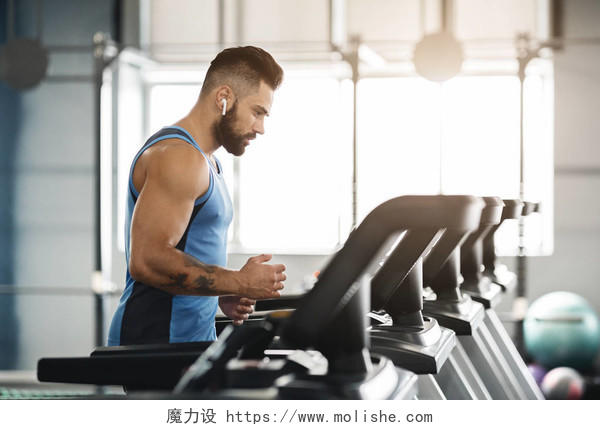 运动型男子在跑步机上跑步在健身房内部